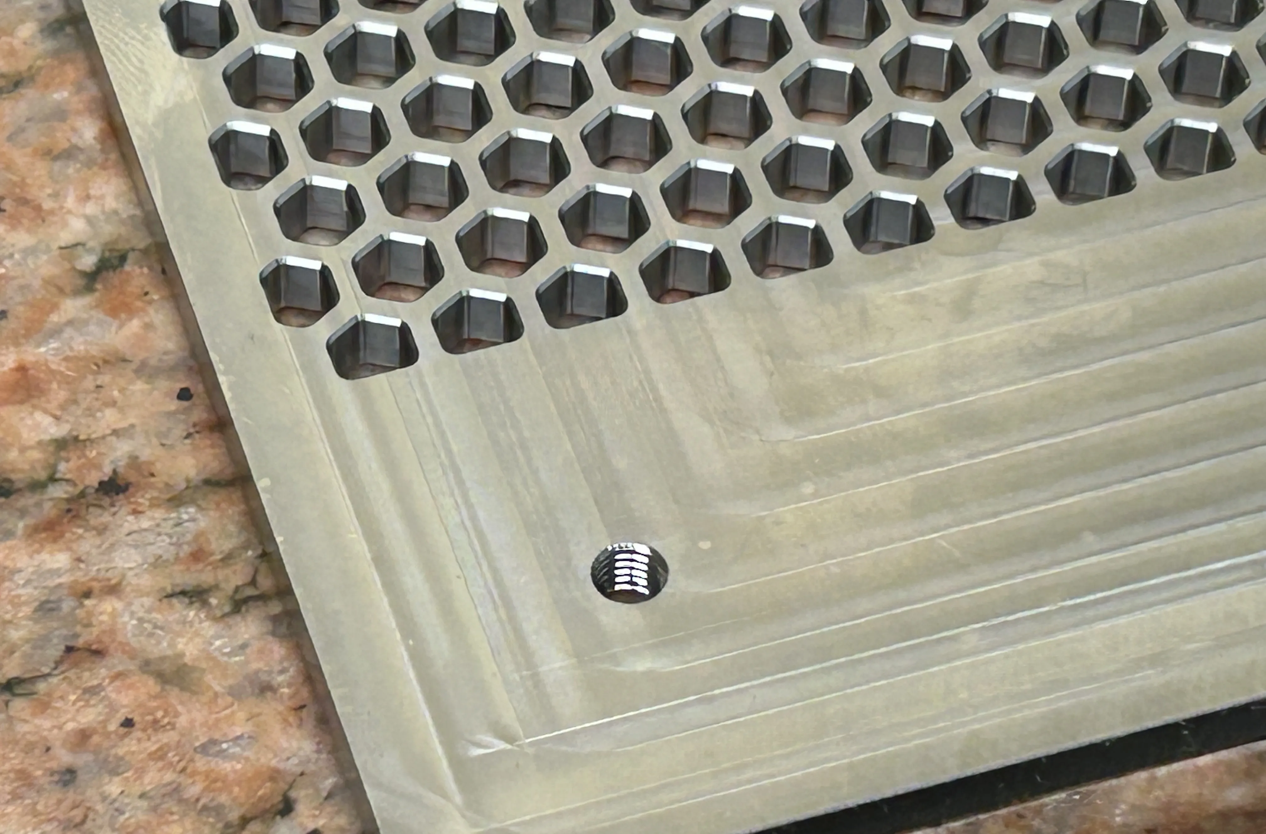Precision-machined stainless steel plate with a honeycomb array of hexagonal pockets